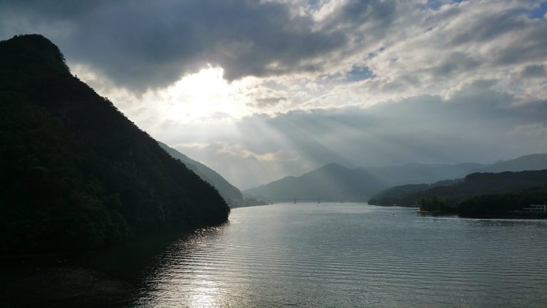 Peaceful sunset light breaking through clouds over calm water