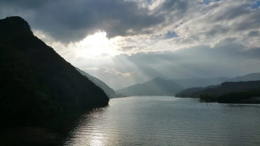 Peaceful sunset light breaking through clouds over calm water